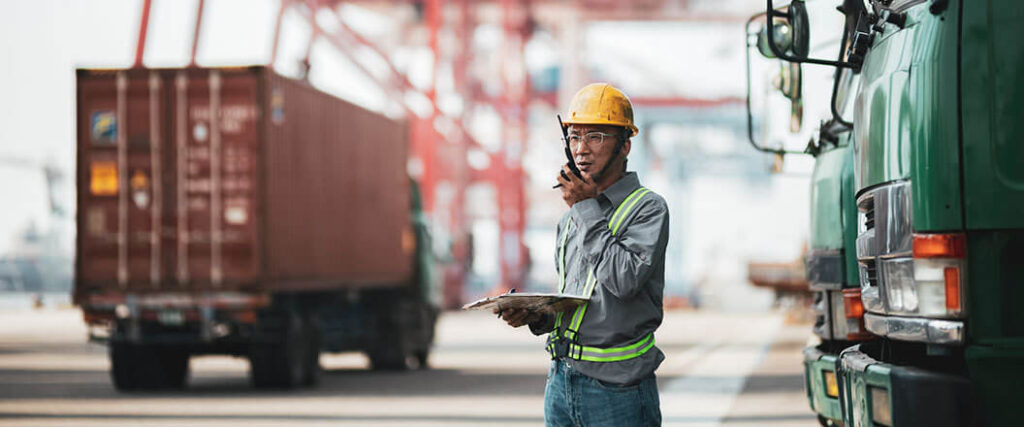 ocean freight forwarding process as man in container yard speaks into a walkie talkie