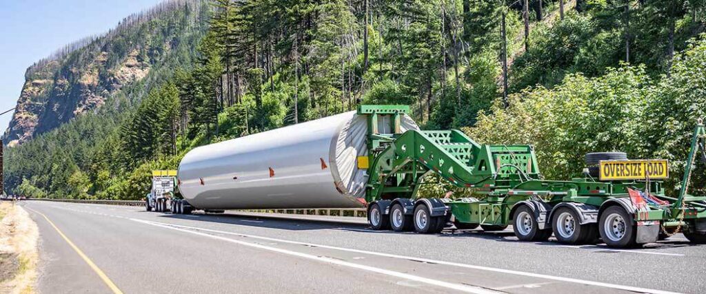 A long cylindrical piece of freight being transported by truck