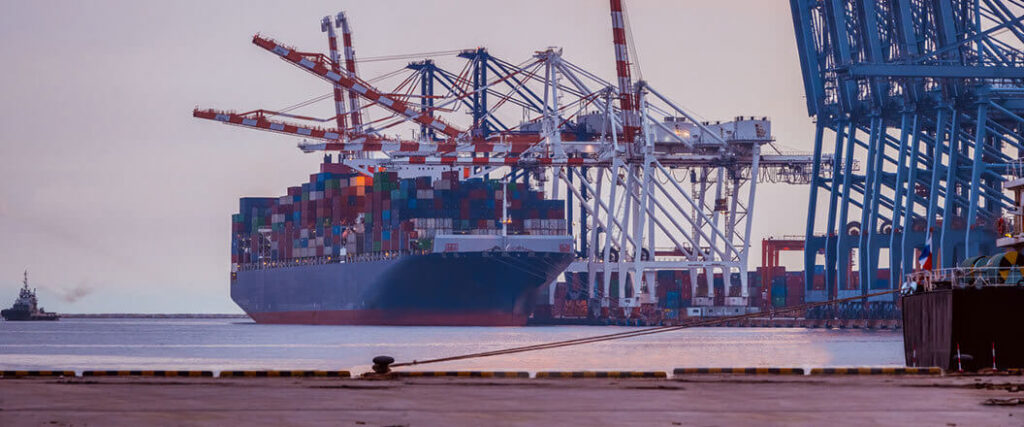 loaded container ship pulled up to several container cranes